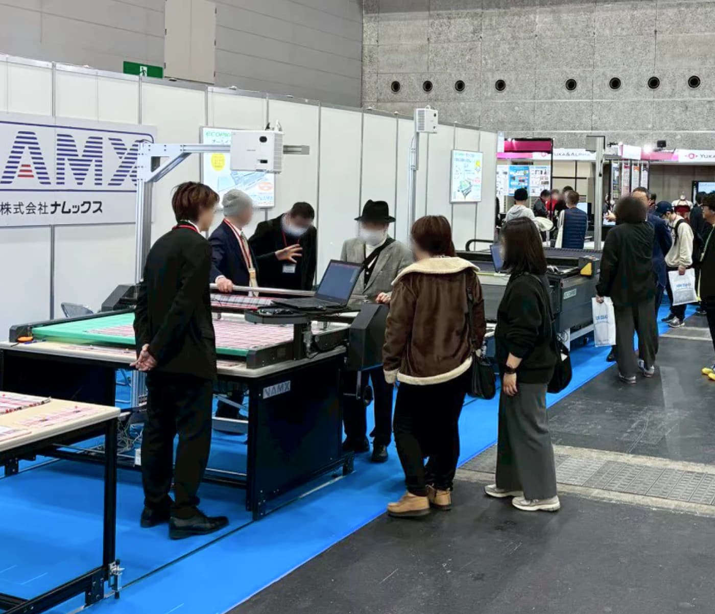 ASM OSAKAの展示ブースで、実機を前に説明を受ける来場者。